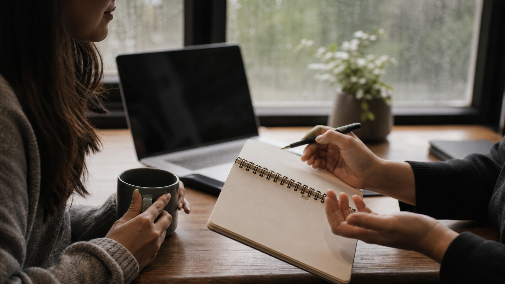 A warm, realistic Aotearoa office scene with two colleagues sharing a notebook beside a laptop, soft window light, no readable text