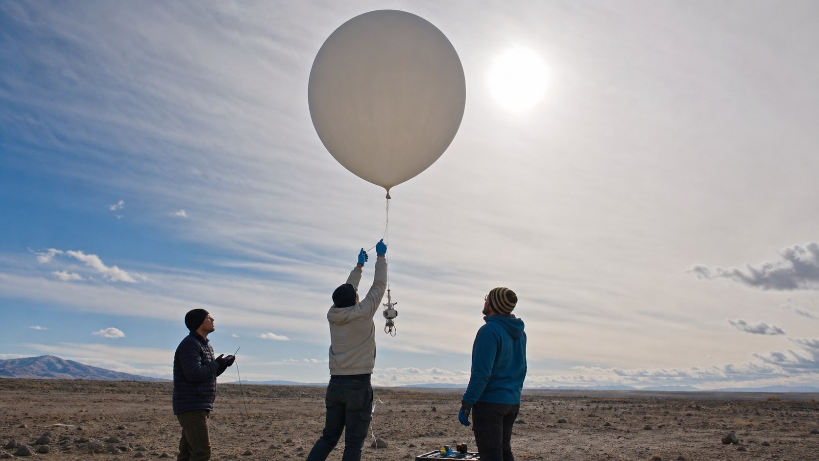 Researchers releasing a scientific balloon under a bright hazy sun